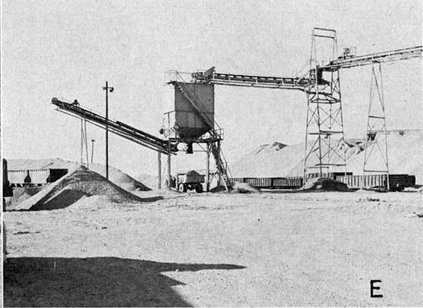 Black and white photo of high conveyor belt moving material into truck.