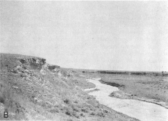 Small flat-toped bluff, steep side, resistant bed at top, above creek bed fileld with sand. No trees; grasses and small brush.