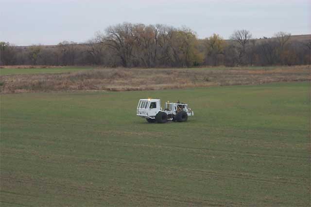 Vibroseis truck in field; young wheat just coming up.