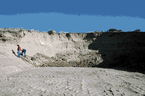 Two men standing in small gravel pit, no more than 15-feet deep and a little wider.